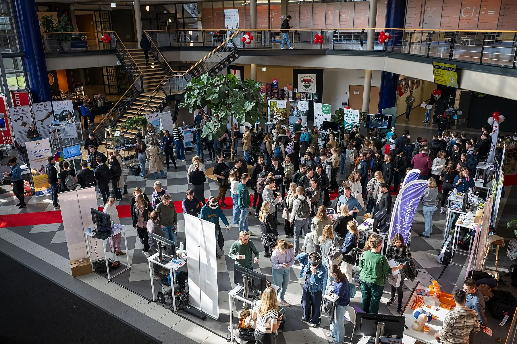 Drukbezochte beursvloer in een atrium, van bovenaf gezien