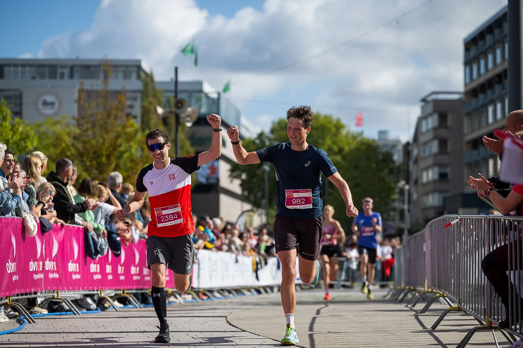 Twee hardlopers juichen bij de finish van een stadsloop
